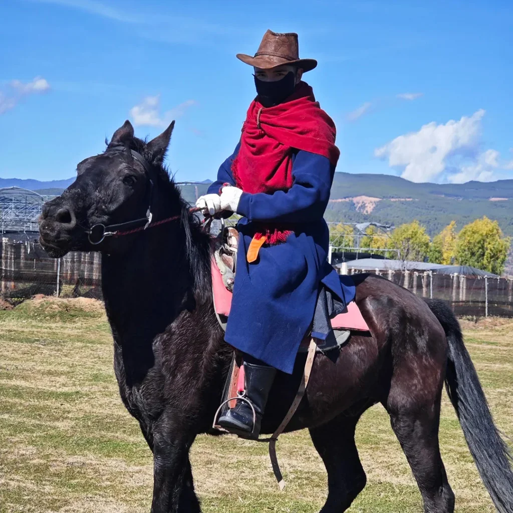 Horseback riding at Lashi Lake 在 拉市海 草地上,一位遊客身著戶外服騎著黑馬,背景是開闊高原與遠山,展現悠閒自然的騎馬體驗