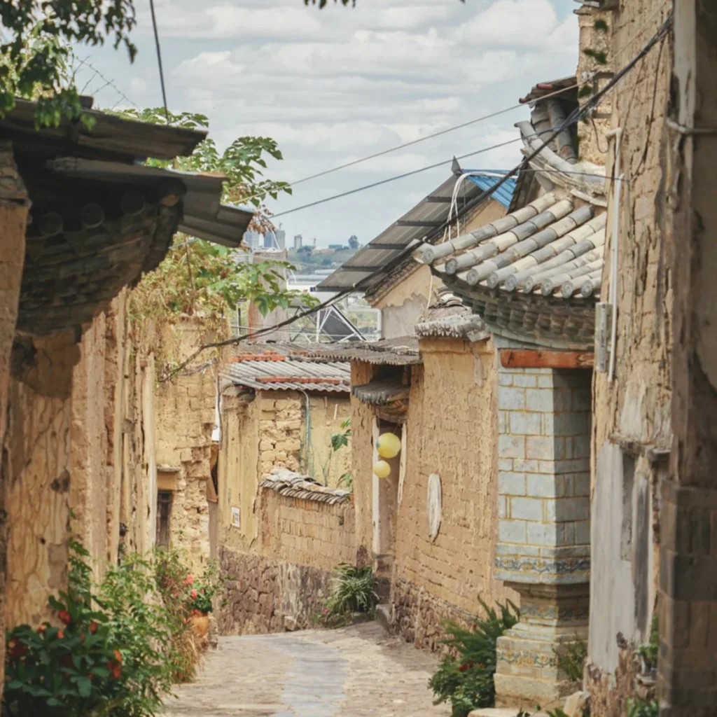 Tuanshan Folk Houses 雲南團山民宅古村巷道景觀,狹窄石板路兩側是傳統土牆與瓦頂民居,老屋牆面帶有歲月痕跡,屋簷與綠植相互點綴,展現團山民宅保存完整的歷史建築與寧靜古村生活氛圍