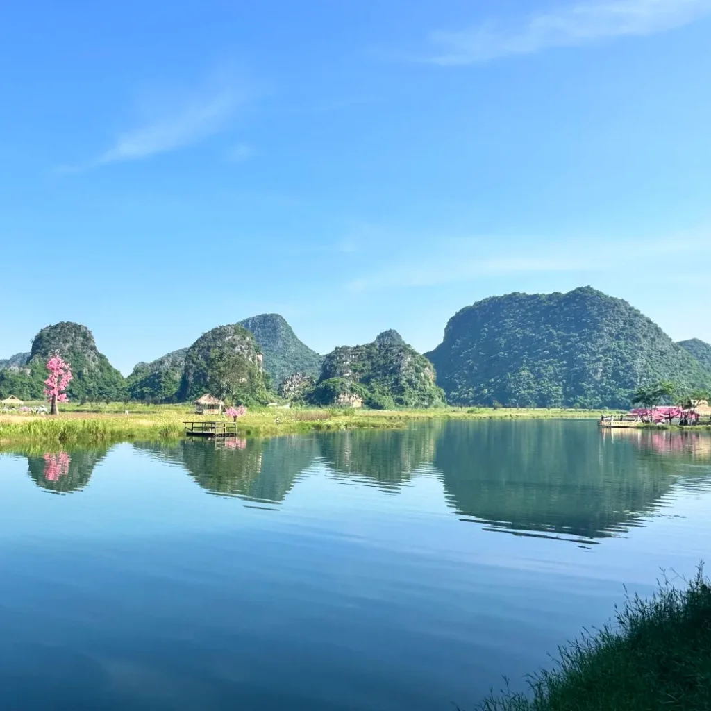 Filming location of Eternal Love 普者黑拍攝地壯麗的綠色喀斯特山丘倒映在平靜的藍色湖泊中,岸邊點綴著粉紅色的桃花樹。
