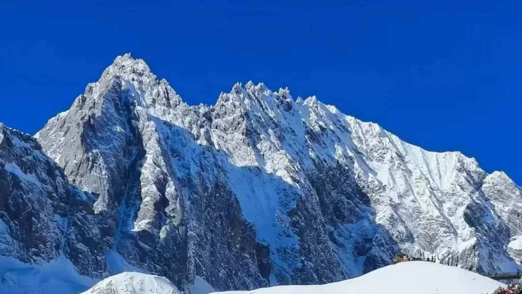 Jade Dragon Snow Mountain 2 雲南麗江玉龍雪山,雄偉鋸齒狀積雪山峰聳立於澄澈深藍天空下,山腳有小型觀景平台。