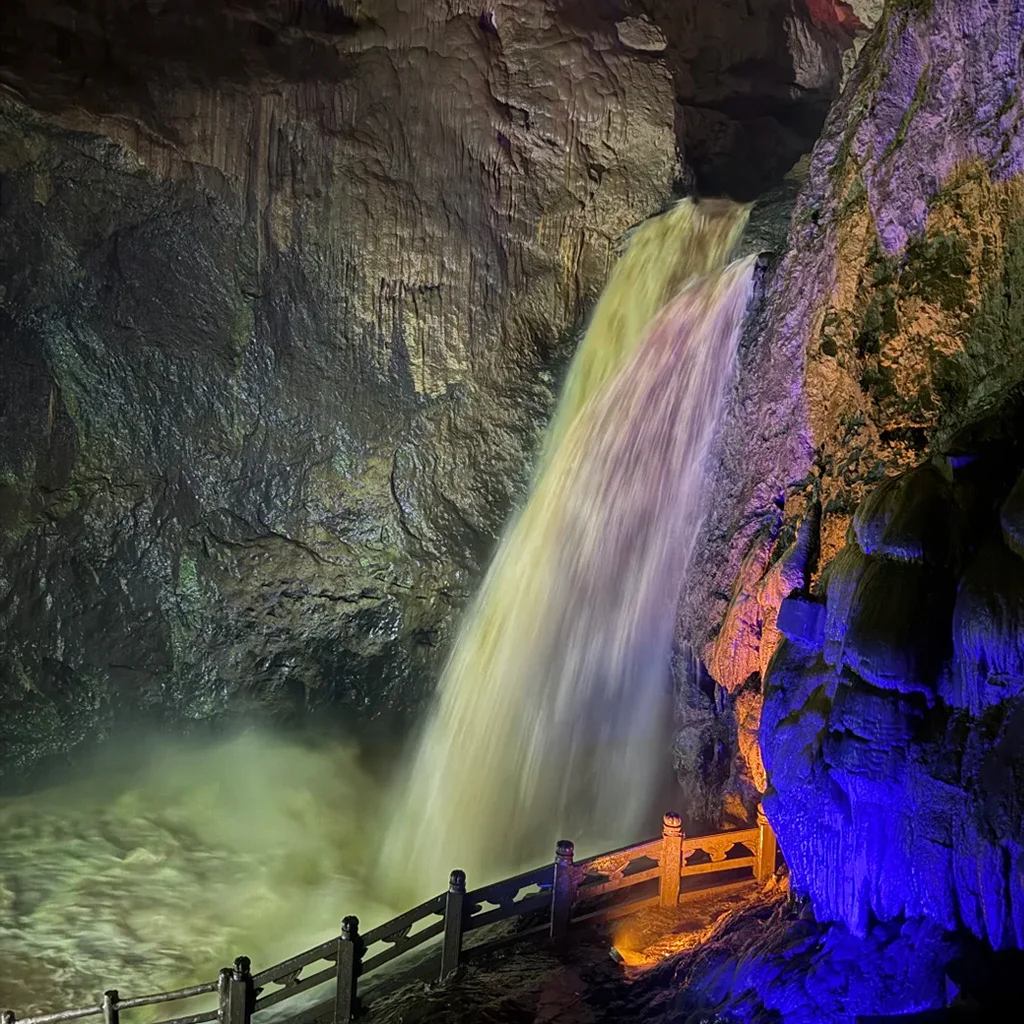 Jiuxiang Scenic Area1 九鄉溶洞內壯觀的地底瀑布,水流從岩壁傾瀉而下,在紫色與藍色的燈光投射下顯得神祕而震撼。